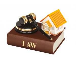 Law book with gavel and model of house.