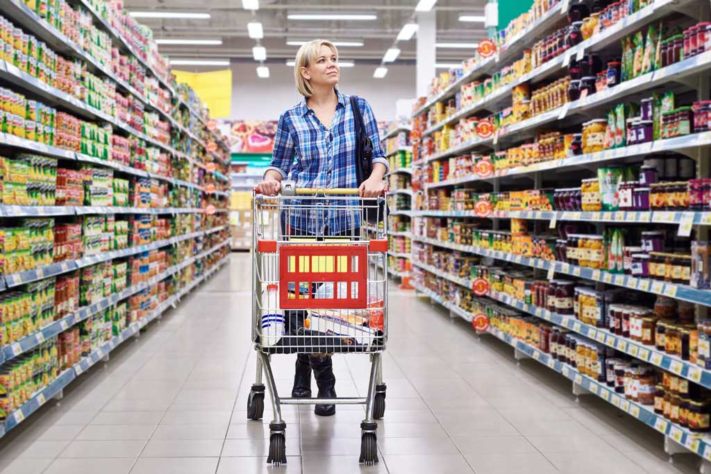 Woman walking down the aisle of a grocery store.