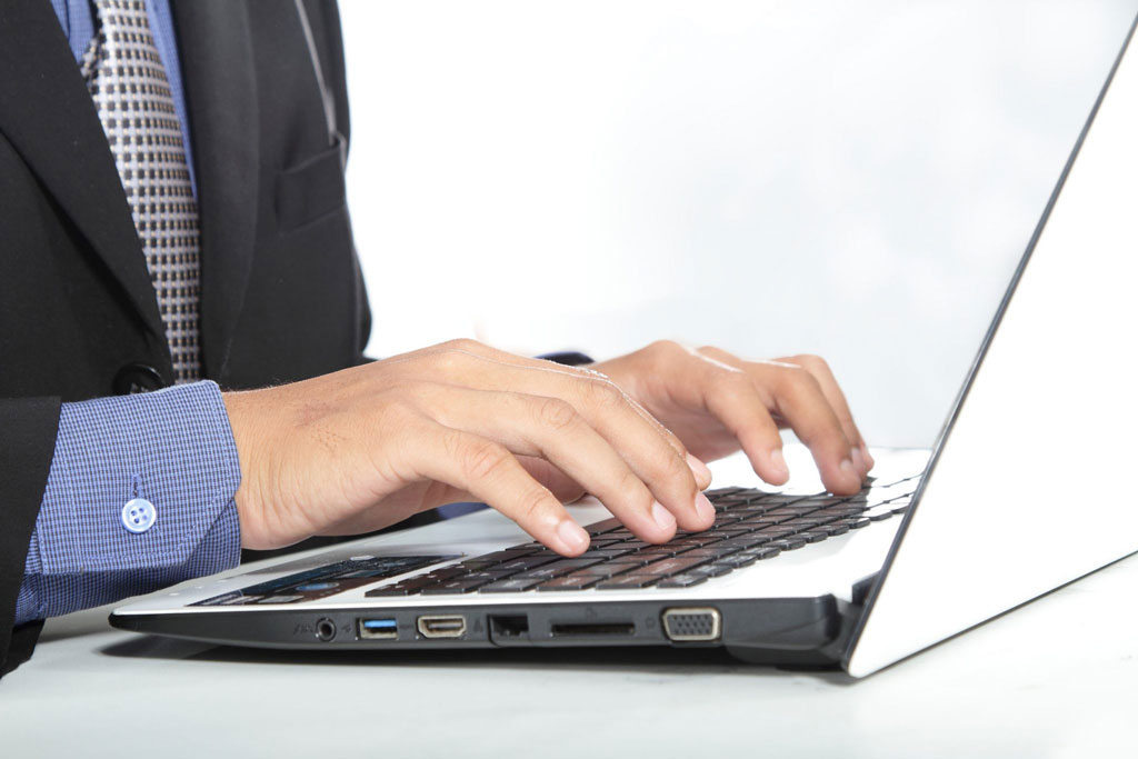 Business person typing on laptop.