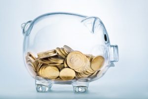Transparent piggy bank with coins inside.