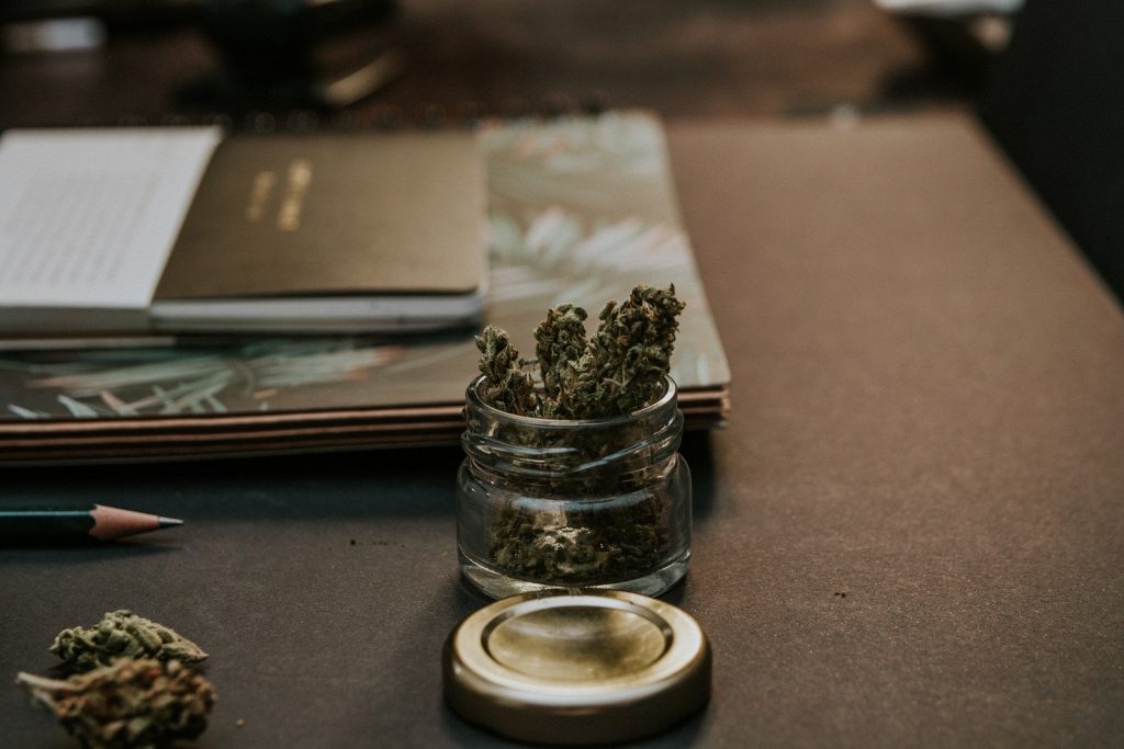 Marijuana in a small jar on desk.