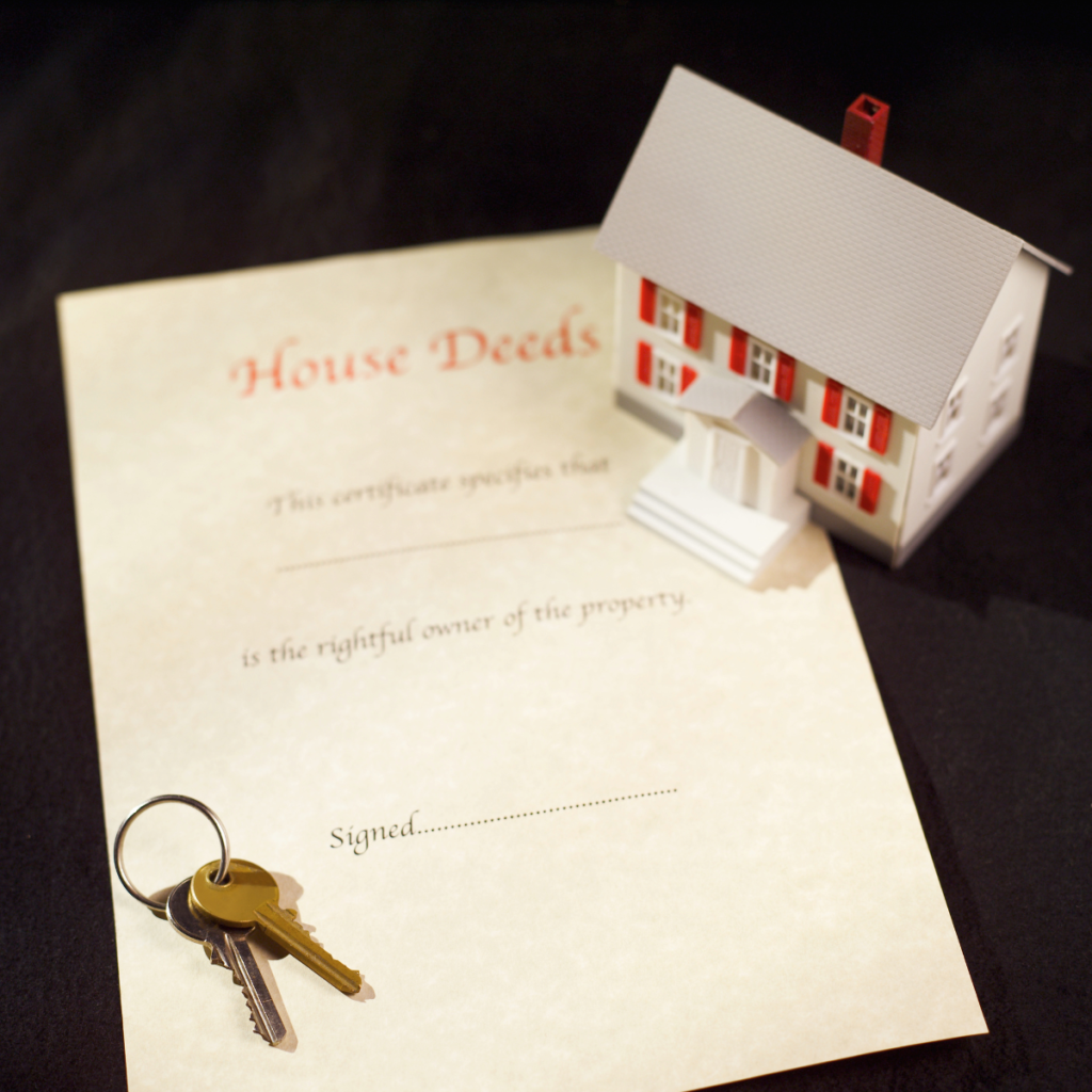 Small model home on a desktop with keys beside it.