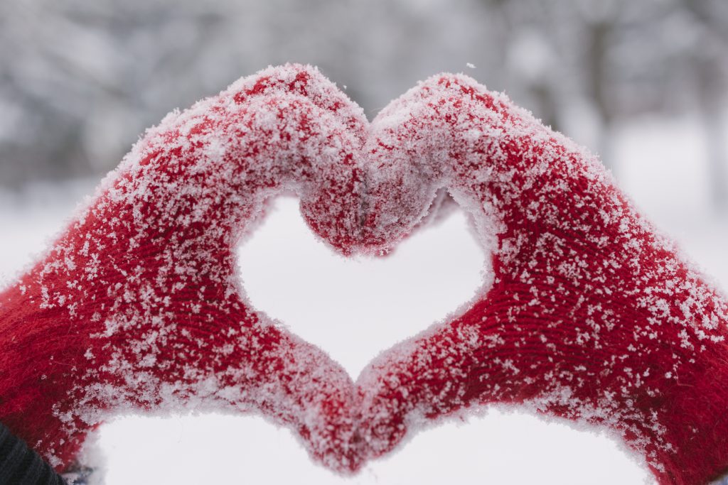 Heart shape made with two hands with snow in the background.