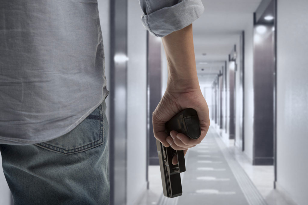 Armed man walking down an office hallway.