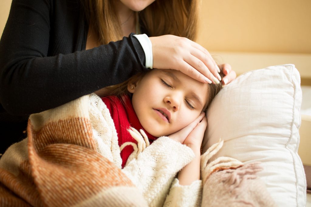 A sick child lying down with her mother by her side.