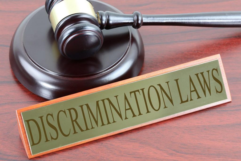 Discrimination Laws sign on top of a desk beside gavel.