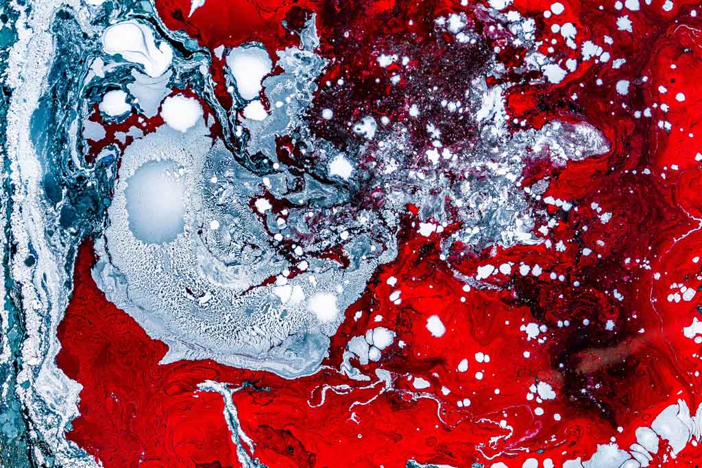 Abstract mixing of light blue and red liquids.