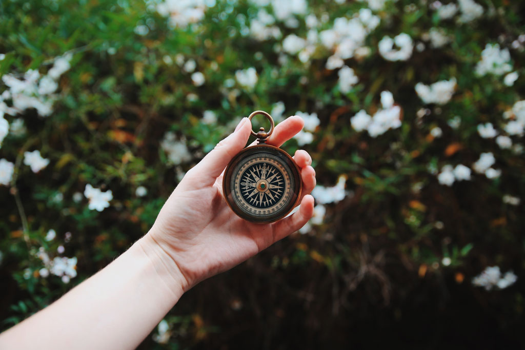 A hand holding a compass.